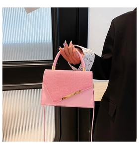 Détail du sac bandoulière rose avec rabat en tissu texturé et barre en métal doré