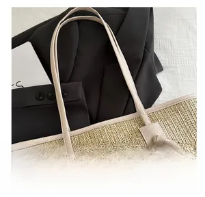 Close-up of woven straw tote bag featuring beige litchi grain leather handles detail