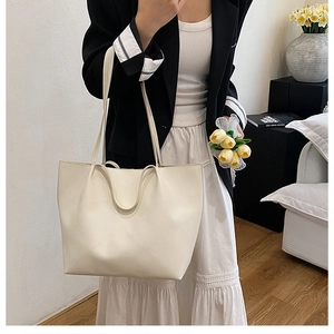 Detail of minimalist cream large tote bag showing smooth faux leather texture and straps