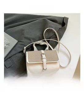 Detail of cream leather handbag with woven texture flap and unique silver metal handle