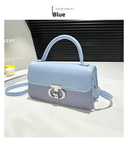 Detail of blue two-tone handbag with metal interlocking clasp and textured fabric