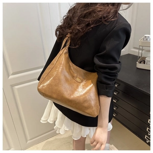 Detail of a brown leather hobo bag showing its soft pleated texture and metal logo