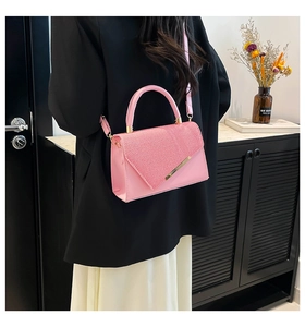 Détail du sac à bandoulière rose avec rabat géométrique et finitions en métal doré