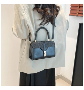 Close-up of black glitter hand bag with gold buckle on a model for scale and style