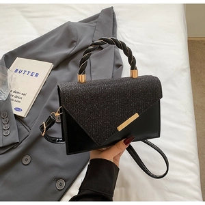 Détail du petit sac carré noir avec rabat scintillant et poignée tressée