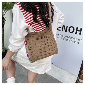 Detail of hand-woven shoulder bag with colorful floral patterns and brown knit texture
