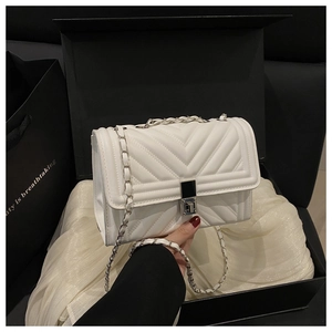 Détail du sac en cuir blanc à surpiqûres en V avec chaîne argentée et fermoir vintage