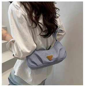 Close-up of blue and white striped underarm bag with gold triangular metal logo detail