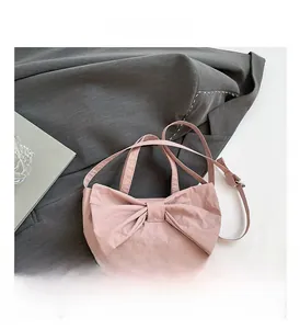 Detailed view of pink pleated shoulder bag with bow decor on neutral fabric background