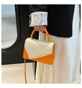 Détail du sac bandoulière en cuir orange avec rabat tissé beige et barre dorée