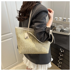 Detail of hand-woven straw tote bag with cream leather straps in a home setting