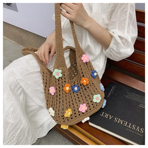 Detail of a brown woven tote bag featuring colorful handmade crochet flower appliques