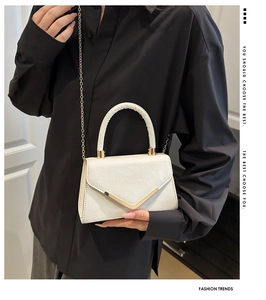Detail of pearlescent white mini bag with glitter texture and V-shaped gold metal clasp