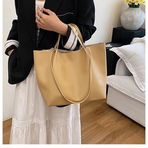Close-up of minimalist khaki tote bag with fine shoulder straps on a female model