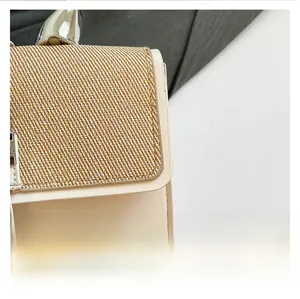 Detail of cream leather handbag featuring brown woven fabric flap and silver metal lock