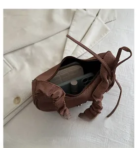 Vue intérieure montrant la capacité d'un sac à bandoulière marron plissé avec accessoires