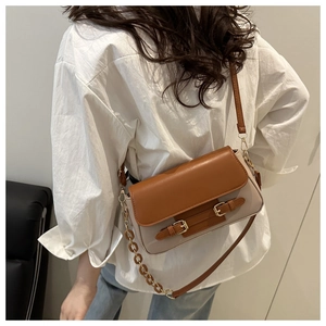 Detail of color-block crossbody bag with amber resin chain and brown leather flap