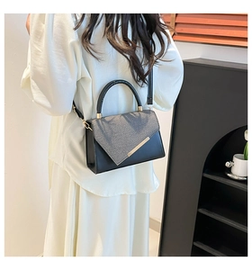 Détail d'un sac bandoulière minimaliste noir et gris porté par un mannequin