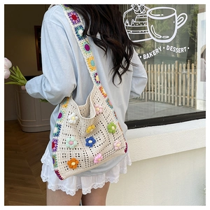Detail of handmade crochet shoulder bag with colorful floral 3D accents and woven strap