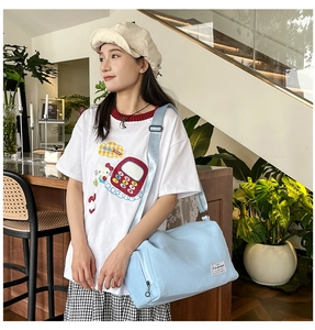 Détail d'un grand sac bandoulière bleu clair avec poche zippée latérale et sangle large