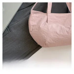 Detail of light pink wrinkled fabric handbag with sturdy top handle and textured finish