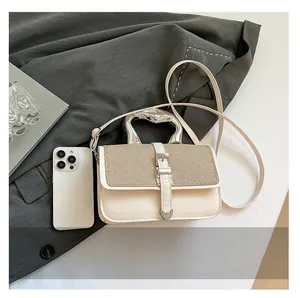 Detail showing the silver metallic handle and textured beige leather of the shoulder bag