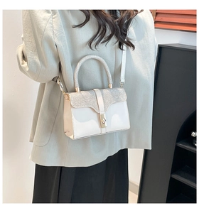 Detail of elegant cream handbag featuring shimmering rhinestone accents and gold metal clasp