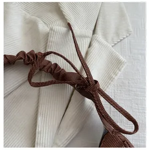 Détail du tissu plissé crème avec bretelles réglables à cordon coulissant tressé marron