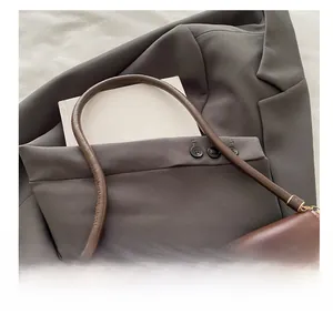 Detalle de bolso en cuero marrón oscuro con asa ergonómica y acabado mate suave