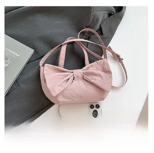 Detail of pink bow handbag with soft pleated fabric and adjustable shoulder strap