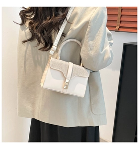 Detail of white leather handbag with sparkling silver glitter flap and gold rotating lock