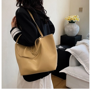 Large beige leather tote bag shown on model for elegant daily commuting style