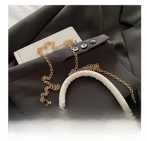 Detailed close-up of premium white textured leather bag with elegant gold metal chain strap