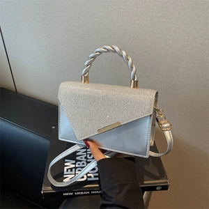 Petit sac à main argenté orné de strass avec poignée en métal torsadé sur des livres