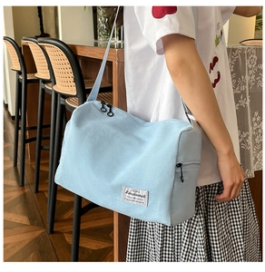 Close-up of light blue canvas crossbody bag with adjustable strap in a cafe setting