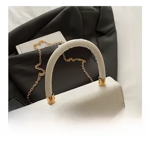 Detail of white glitter handbag with gold metallic hardware and round handle