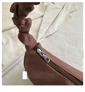 Détail du zip métallique fluide et de l'anse froncée marron du sac à bandoulière