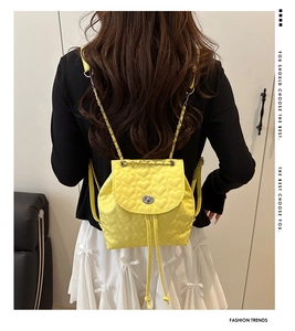 Detail des gelben Mini-Rucksacks mit Herzsteppung, Kettenriemen und Metall-Drehverschluss