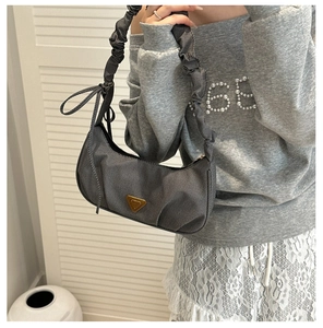 Detail of grey denim baguette bag featuring ruched handle and side ribbon bow decor