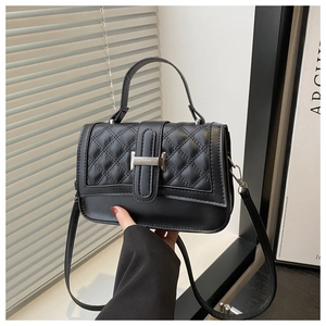Vue détaillée du motif matelassé et de la boucle en métal argenté sur le sac noir bandoulière