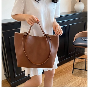 Close-up of brown leather tote bag held by model in a minimalist modern interior