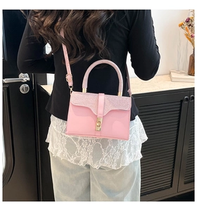 Pink crossbody bag with glitter handle and gold clasp worn in a lifestyle setting