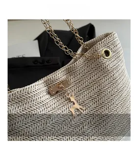 Detail of straw tote with herringbone texture, golden chain strap, and reindeer pendant