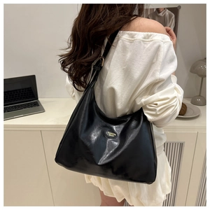 Detail showing high-capacity black leather messenger bag worn over the shoulder