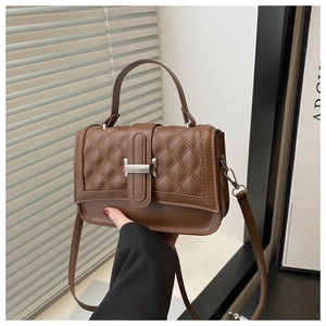 Détail de la texture en cuir matelassé marron et du fermoir en métal argenté en forme de H