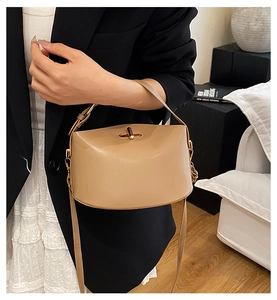 Detail of beige saddle bag with lychee texture leather and golden metal clasp closure