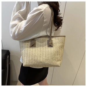 Detail of hand-woven straw tote bag with elegant khaki leather knotted shoulder strap