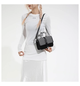 Detail of grey fabric and black leather crossbody bag with unique metal handle