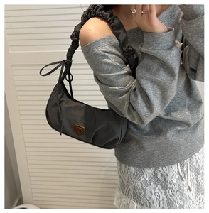 Detail of dark grey pleated strap hobo bag with gold triangle logo on cotton fabric