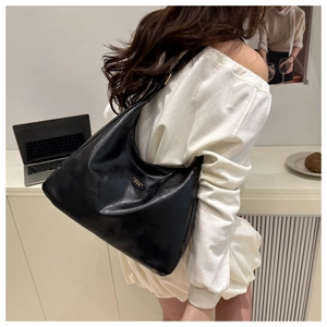 Detail of soft black PU leather tote bag with gold metal plaque and shoulder strap